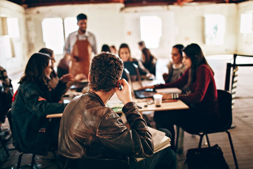 Small group collaborating around a table with notebooks in a workshop